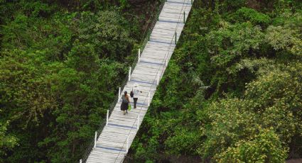 El pequeño Pueblo Mágico de Puebla con cabañas y puente colgante entre bosques, nubes y la sierra